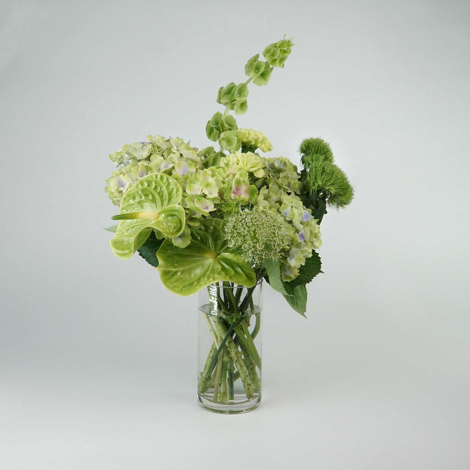Monochrome Bouquet floral arrangement with green blooms and foliage in a vase.
