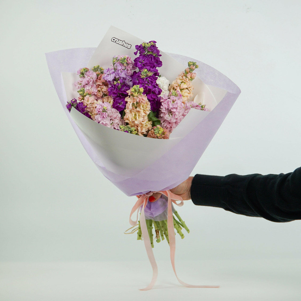 bouquet of Mothers Day flowers, called 'Stock', in purple, lavender, and pale pink, wrapped in light purple paper, tied with a ribbon. Delivered In Melbourne