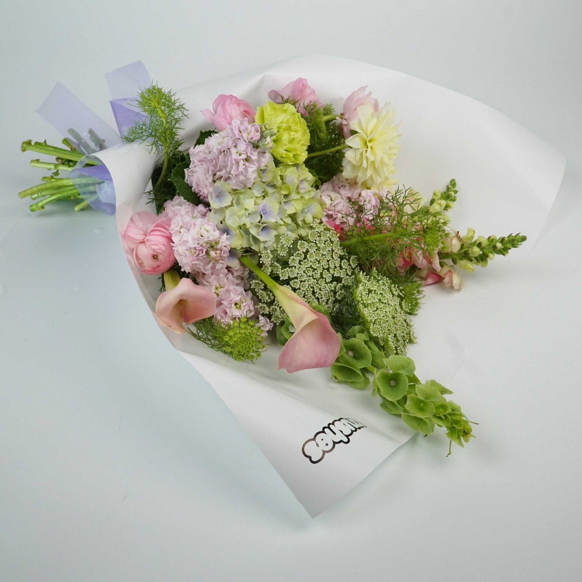 Pastel floral bouquet featuring hydrangea, calla lily, dahlia, ranunculus, carnations, and stock.