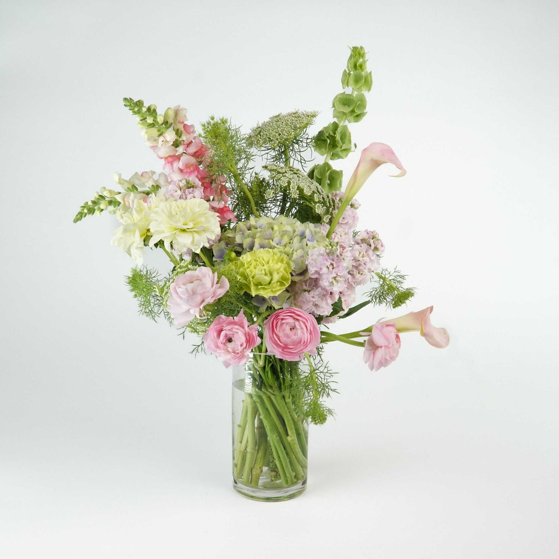 Pastel floral arrangement featuring hydrangea, calla lily, dahlia, ranunculus, carnations, and fluffy stock in a vase.