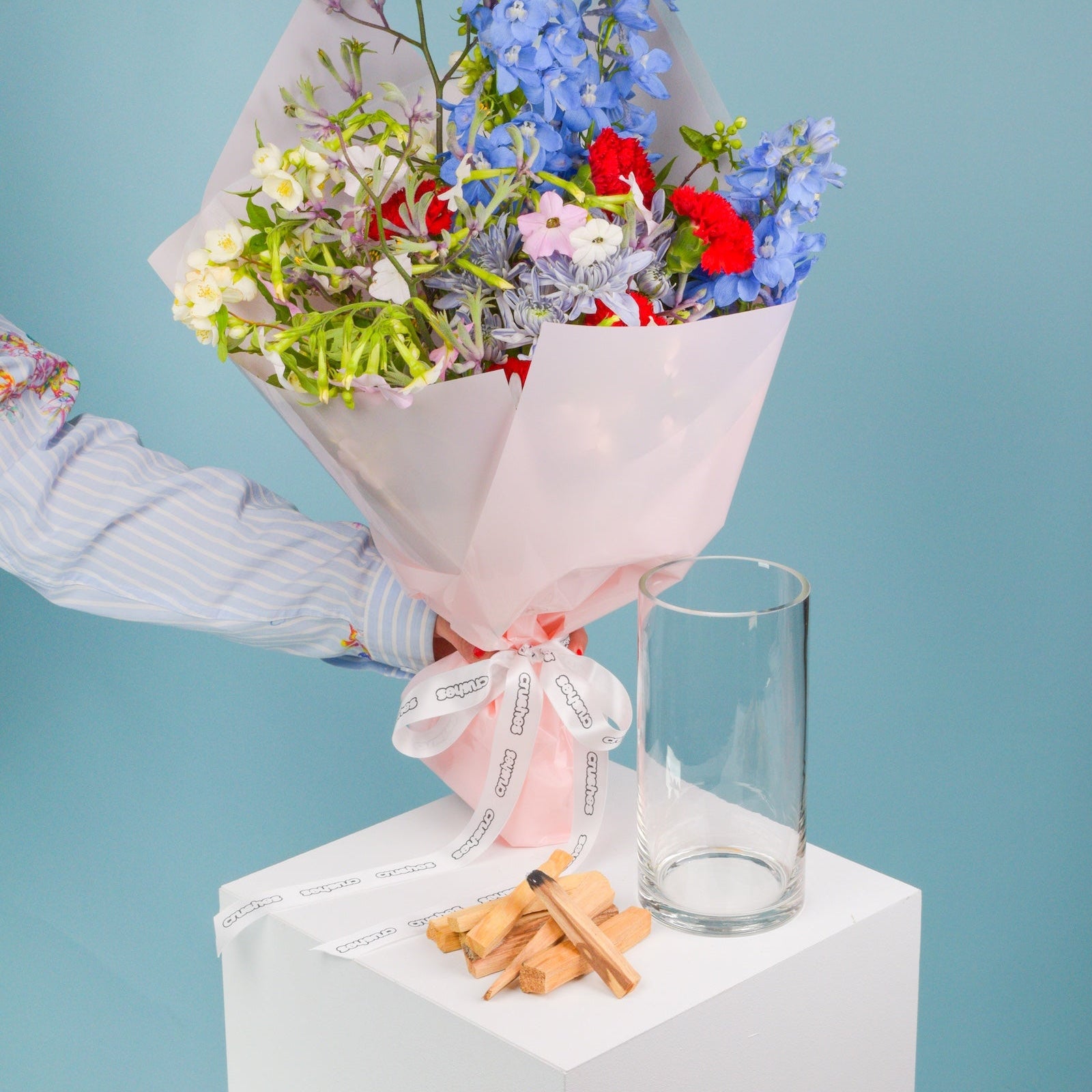 Bouquet of flowers with a glass vase on a white platform against a light blue background