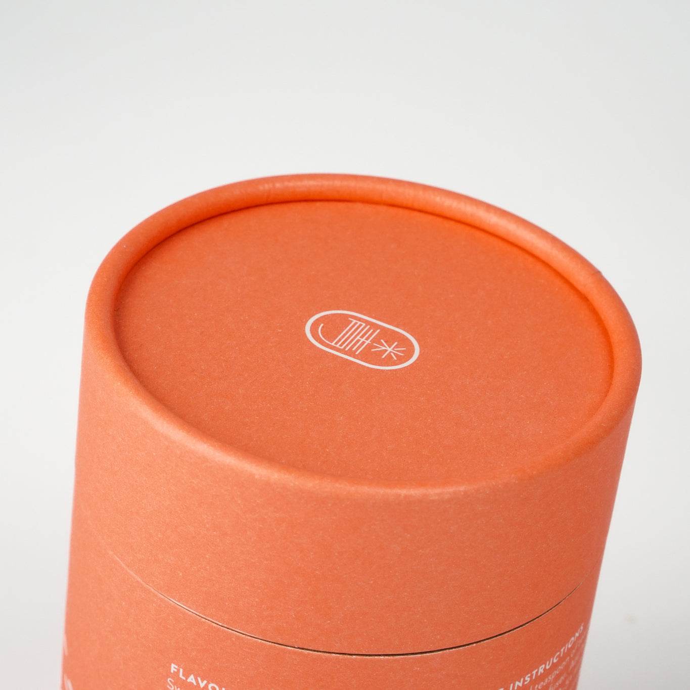 Orange cylindrical packaging of Happy Tea with minimal design.