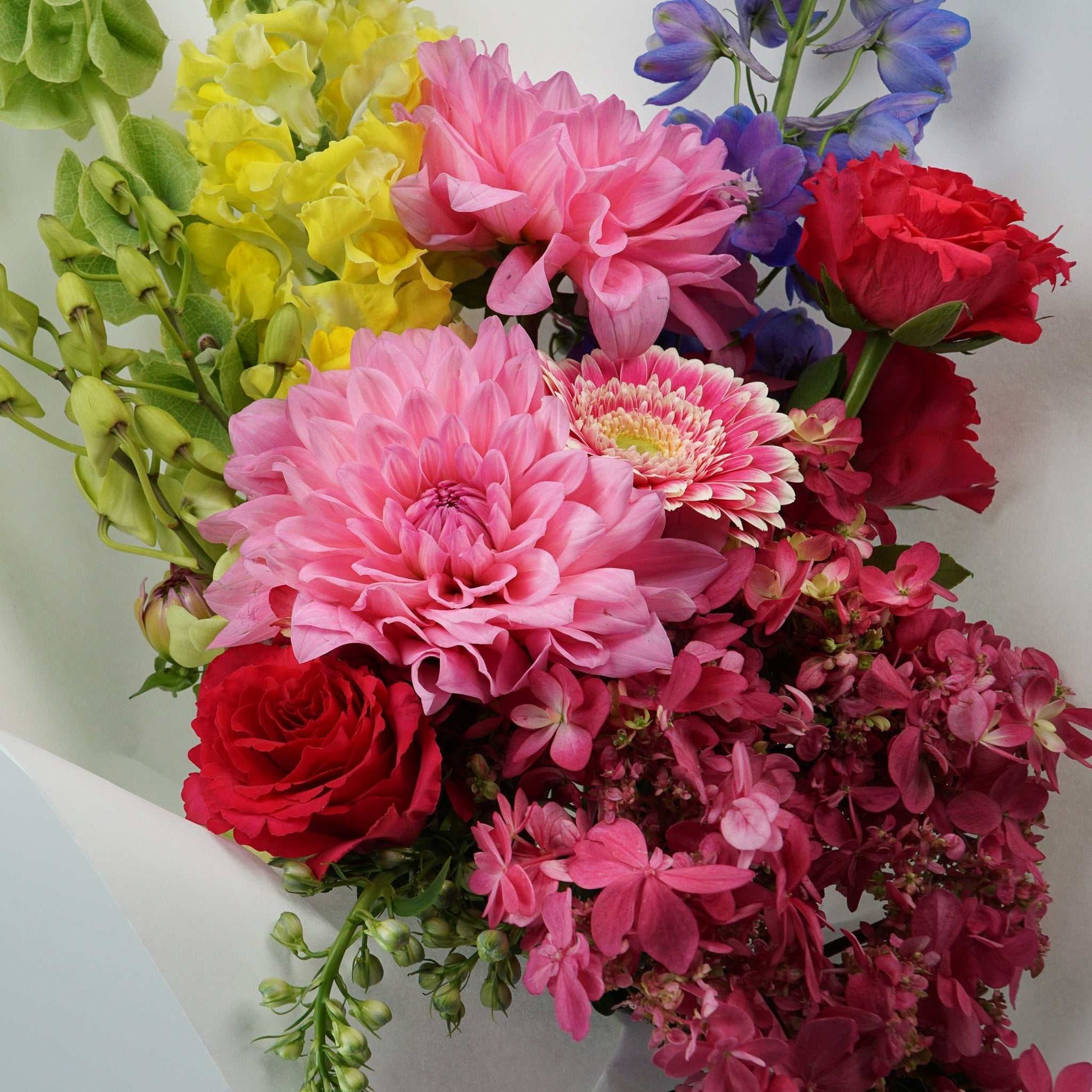 The No.04 - Colour Crush vibrant floral arrangement with seasonal blooms including delphinium, roses, dahlias, gerberas, snapdragons, hydrangea, and molucca balm.