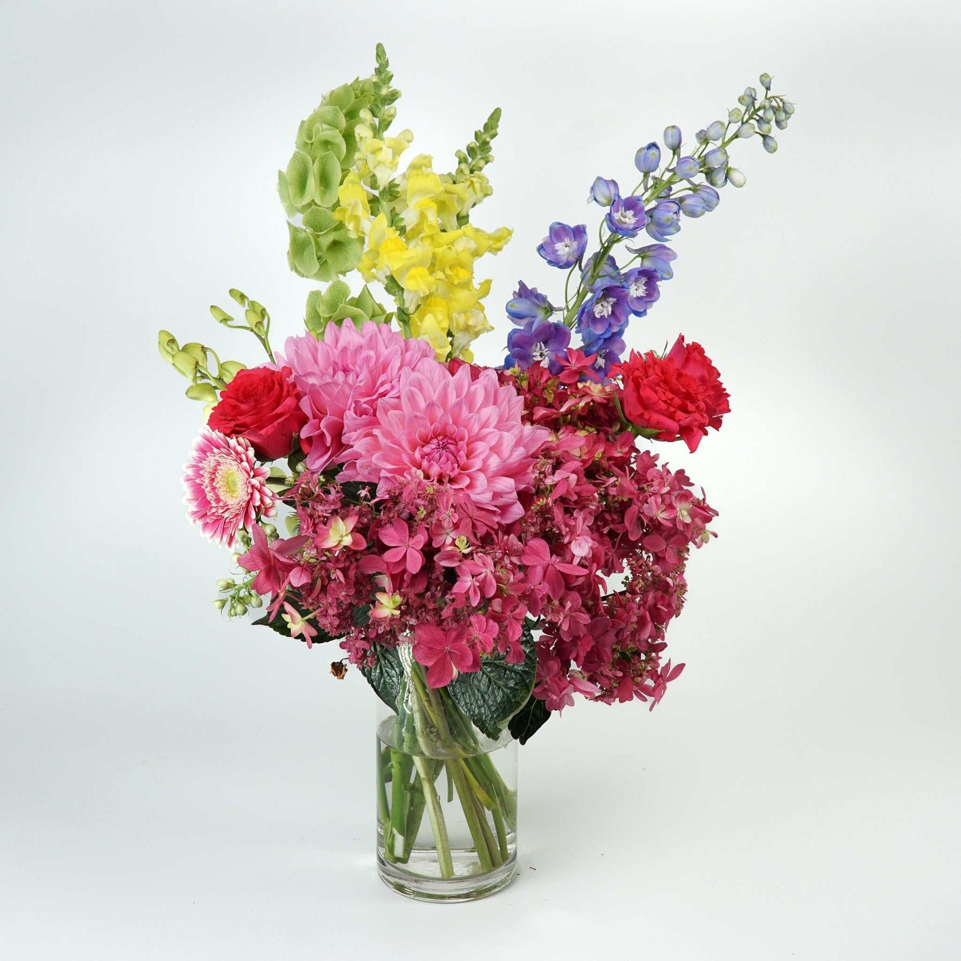 Colorful flower arrangement with roses, dahlias, delphinium, and gerberas in a vase, titled 'The No.04 - Colour Crush'.